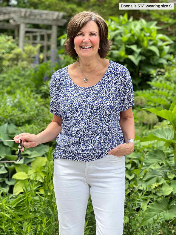Miik founder Donna (5'6", small) smiling wearing Miik's Adisa reversible slouchy dolman top on baby's breath print with a white jeans 