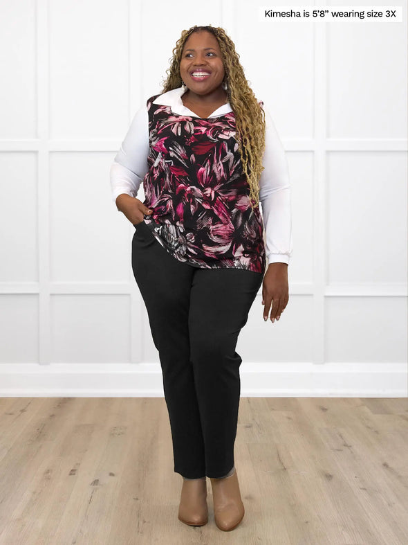 Miik model Kimesha (5'8", 3x, plus size) smiling while standing in front of a white wall wearing Miik's Alanis relaxed tank top in midnight floral on top of a collared shirt in white and a black dress pant #color_midnight-floral