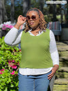 Miik model plus size Erica (5'8", 2x) looking away wearing jeans, a collared white shirt layered on with Miik's Alanis relaxed tank top in green moss