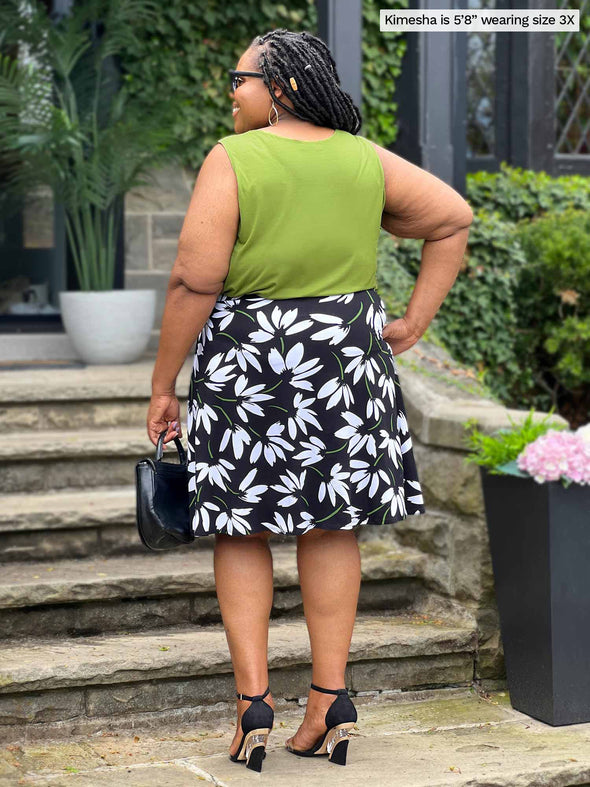Miik model plus size Kimesha (5’8”, 3x) standing with her back towards the camera showing the back of Miik's Alanis relaxed tank top in green moss with a floral skirt 