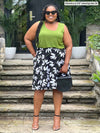 Miik model plus size Kimesha (5'8", 3x) smiling wearing a printed floral skirt along with Miik's Alanis relaxed tank top in green moss and sunglasses 