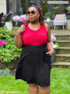Miik model plus size Erica (5'8", 2x) looking away wearing a flouncy pocket skirt in black with a matching belt and Miik's Alanis relaxed tank top in poppy red 