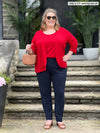 Miik model plus size Kelly (5'7", 3x) smiling wearing a navy dress pant along with Miik's Alanis relaxed tank top in poppy red and a matching colour cropped cardigan 