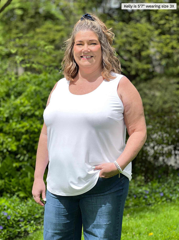 Miik model plus size Kelly (5'7", 3x) smiling wearing Miik's Alanis relaxed tank top in white with jeans 