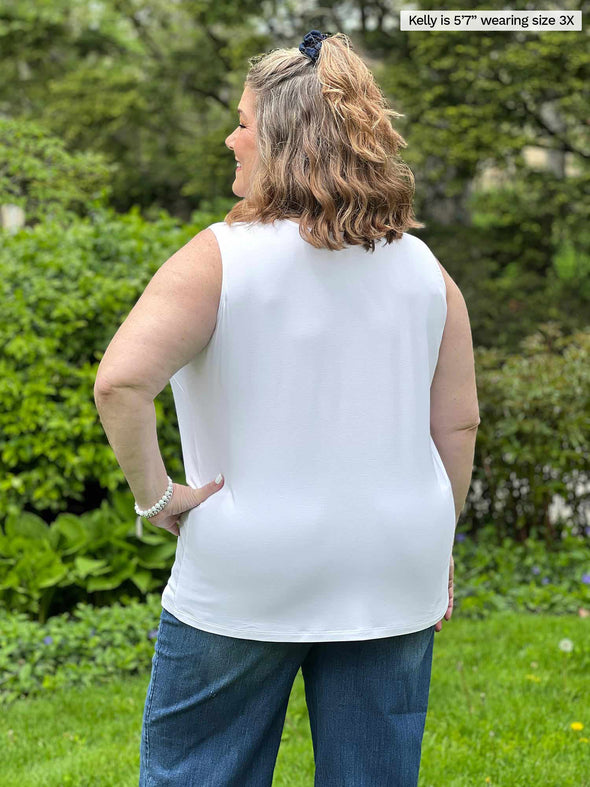 Miik model plus size Kelly (5’7”, 3x) standing with her back towards the camera showing the back of Miik's Alanis relaxed tank top in white