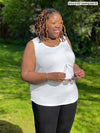 Miik model plus size Erica (5'8", 2x) smiling wearing Miik's Alanis relaxed tank top in white with a black legging 