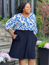 Miik model plus size Kimesha (5'8", 3x) smiling while standing sideway wearing Miik's Alara pocket swing skirt in navy with a ink leaf blouse tucked in