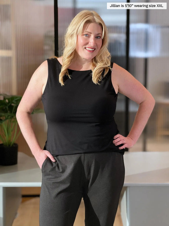 Miik model Jillian (5'10", xxlarge) smiling while standing in a office wearing Miik's Amina reversible tank shelf bra in black with a charcoal jogger
#color_black