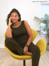 Miik model Meron (5'3", xsmall) sitting on a yellow lounge chair and looking away wearing Miik's Amina reversible tank shelf bra in olive with a dress pant in the same matching colour 
#color_olive 