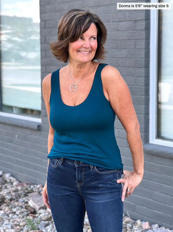 Miik founder Donna (5'6", small) smiling and looking away wearing Miik's Amina reversible tank shelf bra  in teal with jeans 
#color_teal 