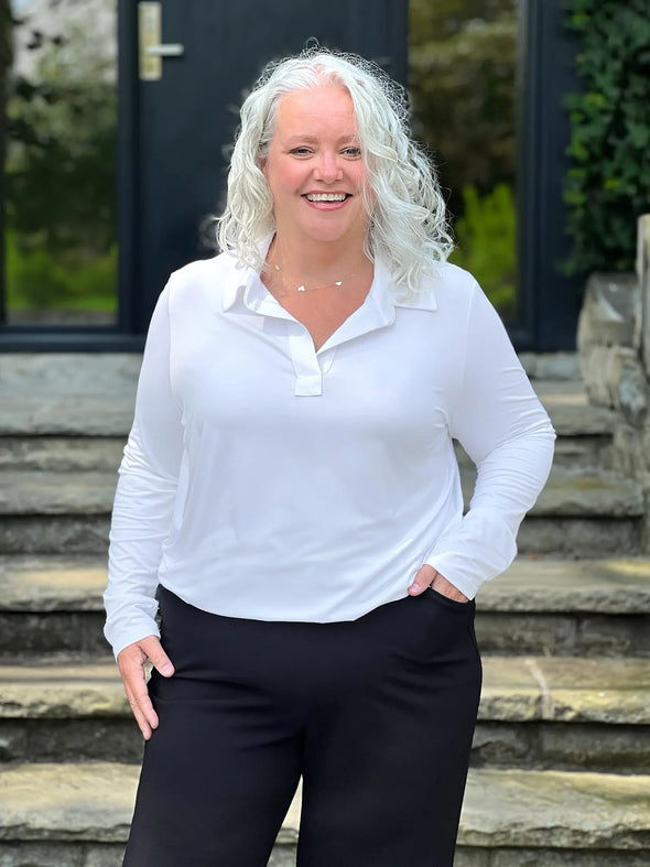 Miik model Colleen (5'3", xxl) smiling wearing Miik's Arianna collared shirt in white with a black wide leg pant. #color_white 