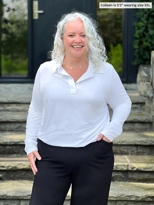 Miik model Colleen (5'3", xxl) smiling wearing Miik's Arianna collared shirt in white with a black wide leg pant. #color_white 