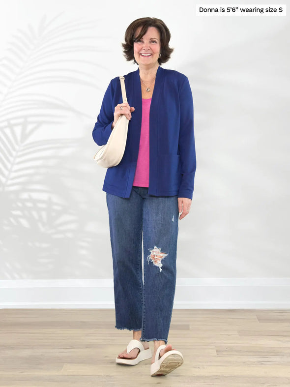 Miik founder Donna (5'6", small) smiling wearing a pink top with ripped jeans and Miik's Arlon cardigan with pockets in marine blue #color_marine-blue