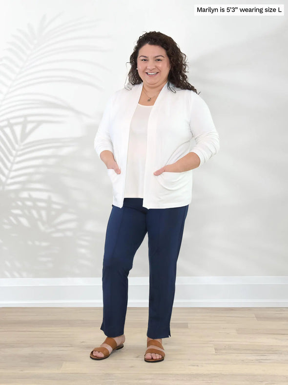 Miik model Marilyn (5'3", large) smiling with both hands on pockets wearing Miik's Arlon cardigan with pockets in natural with a navy dress pant #color_natural