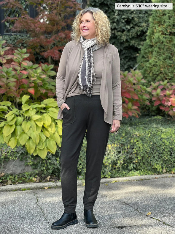 Miik model Carolyn (5'10", large) smiling and looking away wearing Miik's Ashton patch pocket jogger in charcoal with a top and cardigan in the mushroom melange color #color_charcoal 