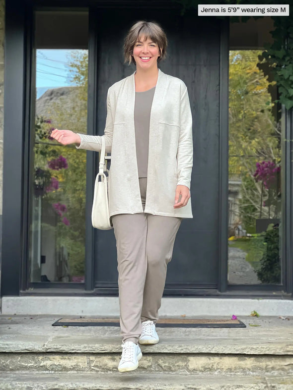 Miik model Jenna (5'9", medium) smiling wearing Miik's Ashton patch pocket jogger in mushroom melange with a top in the same matching colour and a fleece cardigan in oatmeal melange #color_mushroom-melange  