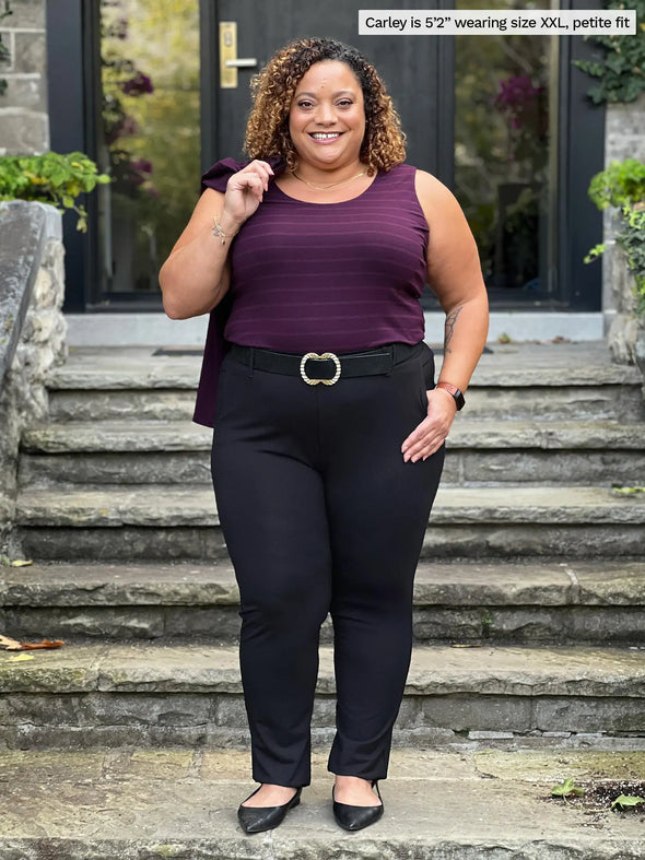 Miik model Carley (5'2", xxlarge) smiling wearing Miik's Asia mid-rise slim pant in black, petite fit, with a belt and a striped tank top in port #color_black 