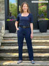 Miik model Lex (5'2", xsmall) smiling wearing Miik's Asia midi-rise slim pant in short length in navy with a square neck top in the same colour 