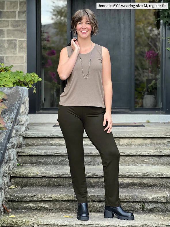 Miik model Jenna (5'9", medium) smiling wearing Miik's Asia mid-rise slim pant in olive, regular fit, with a tank top in mushroom melange #color_olive 