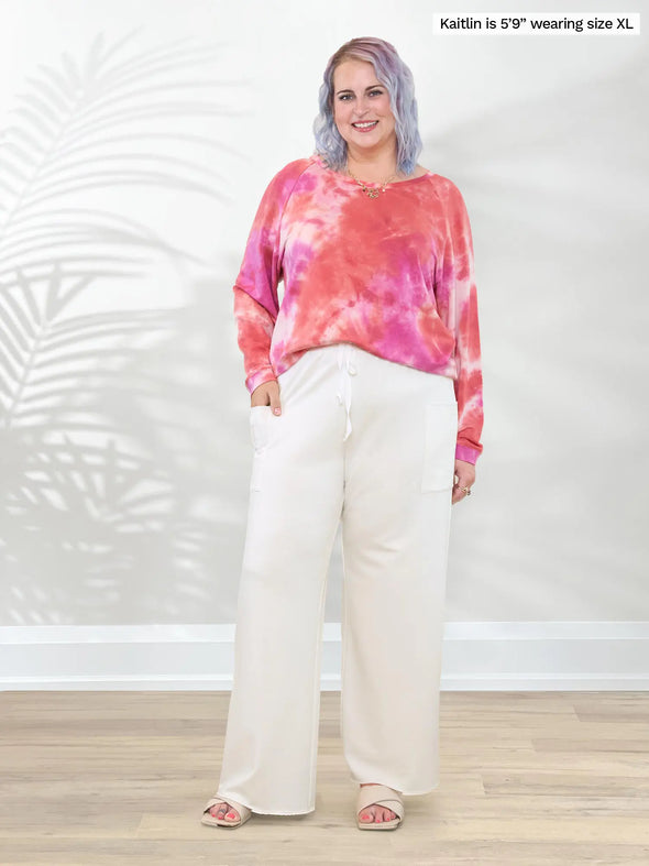 Miik model Kaitlin (5'9", XL/XXL) smiling wearing a  wide leg pant in natural with Miik's Aurelia lightweight french terry sweatshirt in coral reef #color_coral-reef