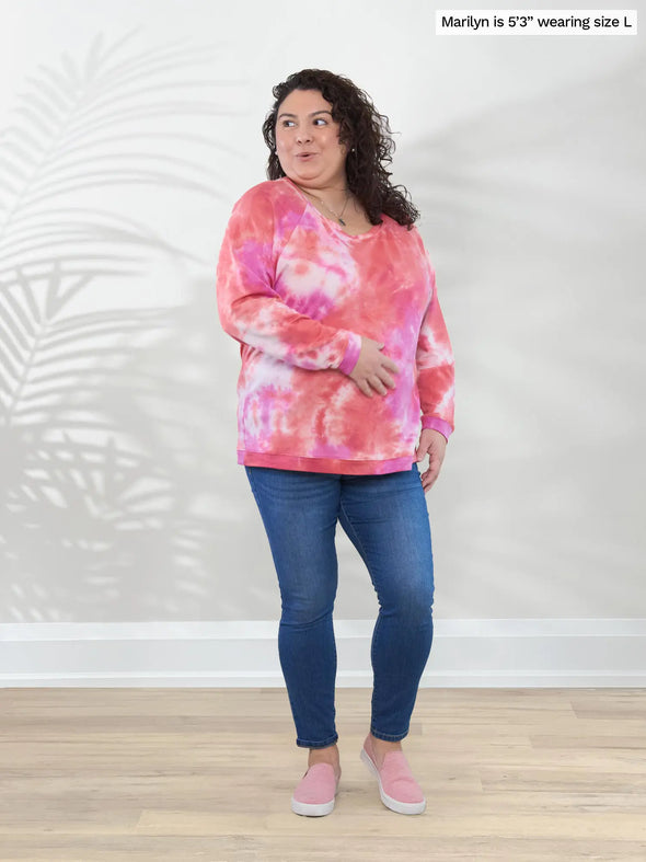 Miik model Marilyn (5'3", large) smiling and looking away wearing Miik's Aurelia lightweight french terry sweatshirt in coral reef with jeans and pink shoes #color_coral-reef