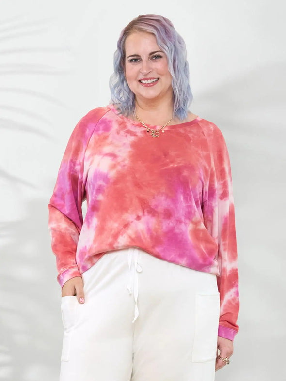 Miik model Kaitlin (5'9", XL/XXL) smiling wearing a  wide leg pant in natural with Miik's Aurelia lightweight french terry sweatshirt in coral reef #color_coral-reef