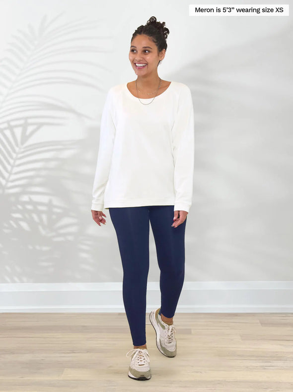 Miik model Meron (5'3", xsmall) smiling and looking away wearing Miik's Aurelia lightweight french terry sweatshirt in natural with a navy legging and sneakers #color_natural