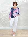 Miik founder Donna (5'6", small) smiling while standing in front of a white wall wearing Miik's Aurelia lightweight french terry sweatshirt in northern lights print with a white capri pant #color_northern-lights 