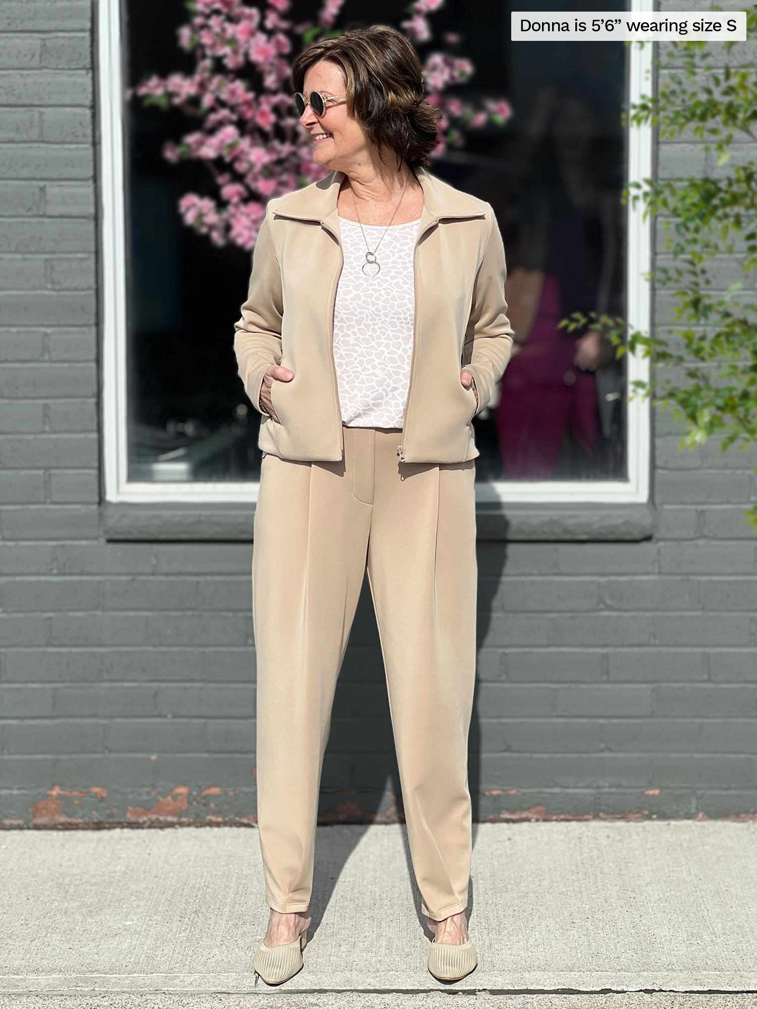 Miik founder Donna (five feet six, size small) standing in front of a window looking away wearing a matching casual suit in wheat: Miik&