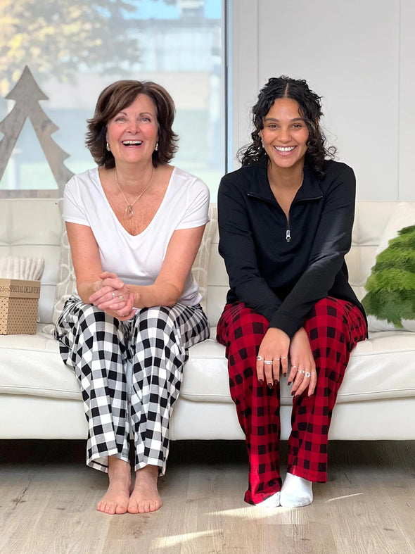 Miik founder Donna and model Meron smiling while sitting on a cozy couch both wearing Miik's Bryce plaid bamboo PJ pant