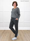 Miik founder Donna (5'6", small) smiling wearing Miik's Cameron luxe fleece jogger with pockets in charcoal with a sweatshirt in granite melange and sneakers #color_charcoal