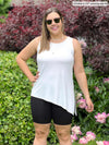 Miik model Christal (5'3", medium) smiling wearing a white asymmetrical tank with Miik's Chalha high waisted mid thigh biker short in black and sunglasses 