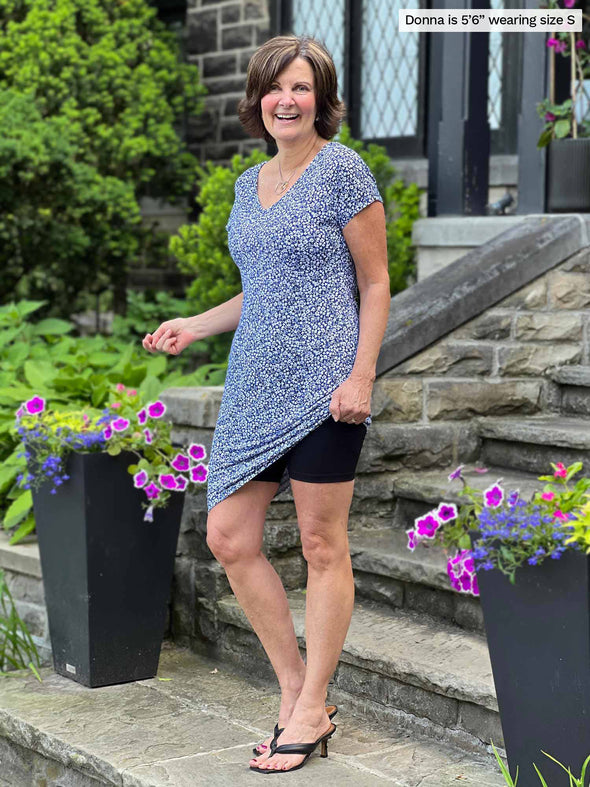 Miik founder Donna (5'6", small) smiling wearing a floral blue dress with Miik's Chalha high waisted mid thigh biker short in black 