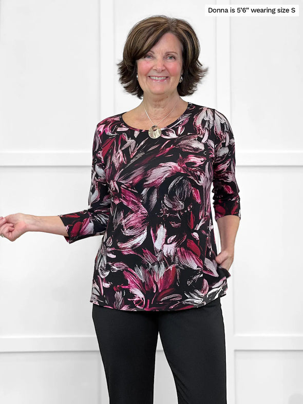 Miik founder Donna (5'6", small) smiling wearing Miik's Chris 3/4 sleeve scoop neck top in midnight floral with a black dress pant #color_midnight-floral 