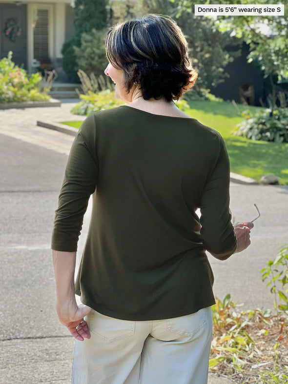 Miik founder Donna (5’6”, small) standing with her back towards the camera showing the back of Miik's Chris 3/4 sleeve scoop neck top in olive 
#color_olive 