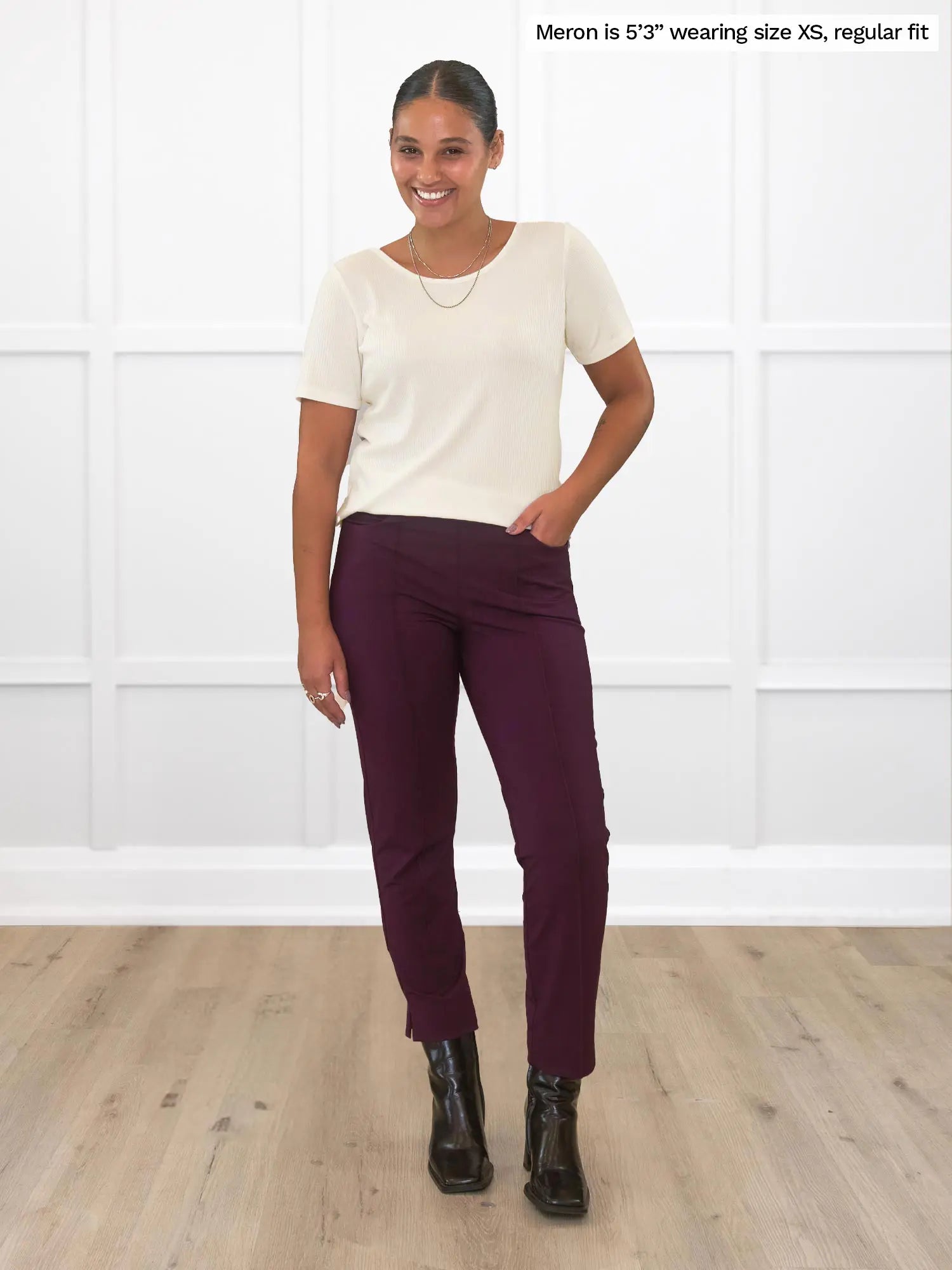 Miik model Meron (53&quot;, xsmall) smiling while standing in front of a white wall wearing Miik&