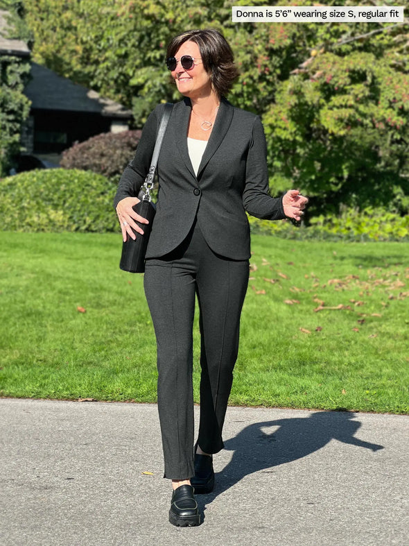 Miik founder Donna, size S, wearing the Christal pull-on pintuck ankle pant in charcoal in regular length with a matching blazer #color_charcoal