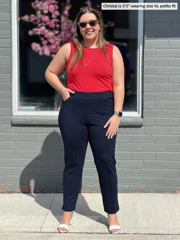 Miik model Christal (5'3', medium, petite) smiling wearing Miik's Christal pintuck pull on ankle pant in navy with a poppy red tank top 
#color_navy