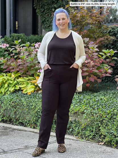 Miik model Kaitlin (size XXL, 5 foot 9) wearing the long length Christal pull-on dress pant in dark chocolate brown with a matching tank and beige cardigan.
