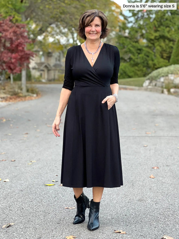 Miik founder Donna (5'6", small) smiling wearing Miik's Claudine tie waist midi dress in black with matching colour boots #color_black