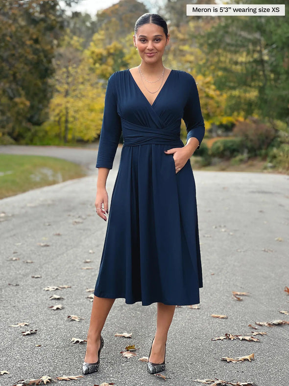 Miik model Meron (5'3", xsmall) smiling wearing Miik's Claudine tie waist midi dress in navy #color_navy