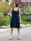 Miik founder Donna (5'6", small) smiling and looking away wearing Miik's Ela reversible pleated sleeveless pocket dress in navy