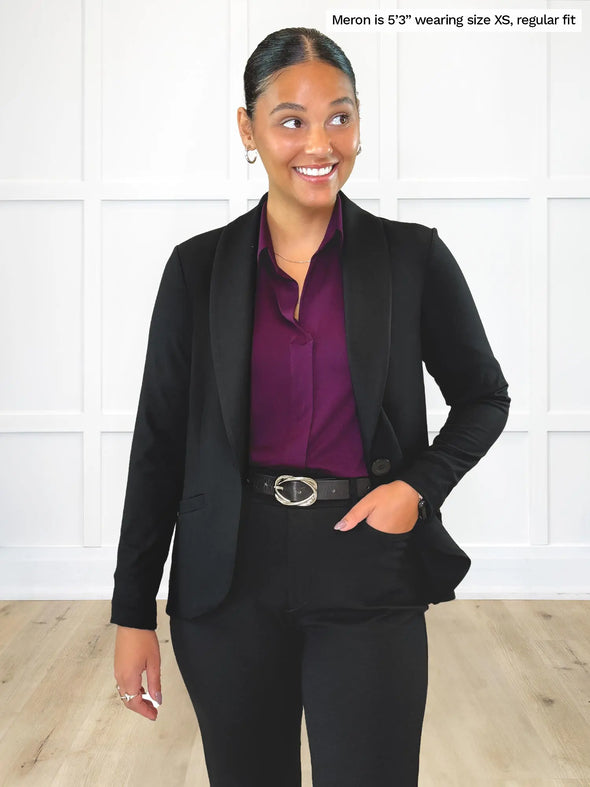 Miik model Meron (5'3", xsmall) smiling and looking away wearing a black suit: Miik's Emily soft blazer, regular fit, with a dress pant and a collared shirt in port #color_black