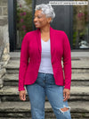 Miik model Keethai (5'5", medium) smiling wearing Miik's Emily soft blazer in cerise, regular fit, with a white tank and a ripped jeans #color_cerise 