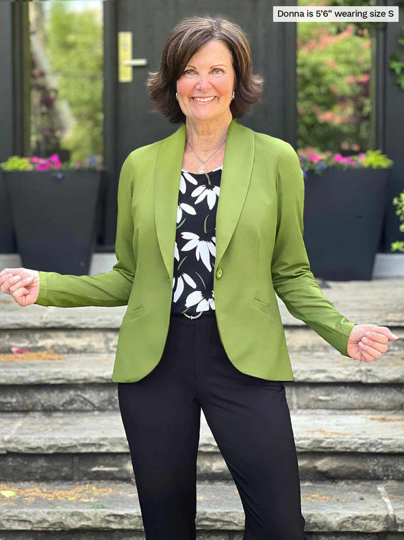 Miik founder Donna (5'6", small) smiling wearing Miik's Emily soft blazer in green moss with a floral printed tank and a dress pant in black