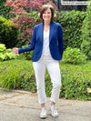 Miik founder Donna (5'6", small) smiling wearing an all white outfit: jeans and v-neck tee along with Miik's Emily soft blazer in ink blue