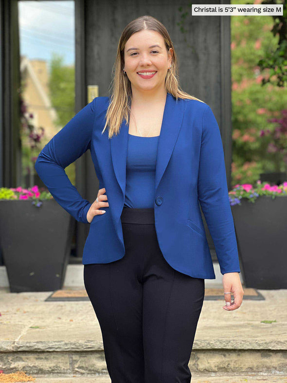 Miik model Christal (5'3", medium) smiling wearing Miik's Emily soft blazer in ink blue with a tank in the same matching colour and a black dress pant