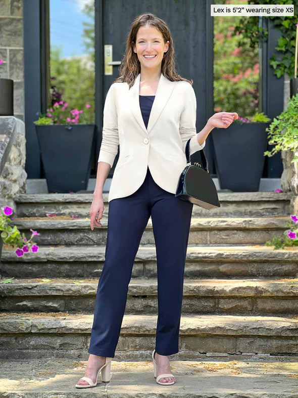 Miik model Lex (5'2", xsmall) smiling wearing a blouse and a pant in navy with Miik's Emily soft blazer in natural 