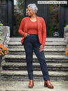 Miik model Keethai (5'5", medium) smiling wearing Miik's Emily soft blazer in paprika melange, regular fit, with a tank in the same matching colour and a navy dress pant #color_paprika-melange 