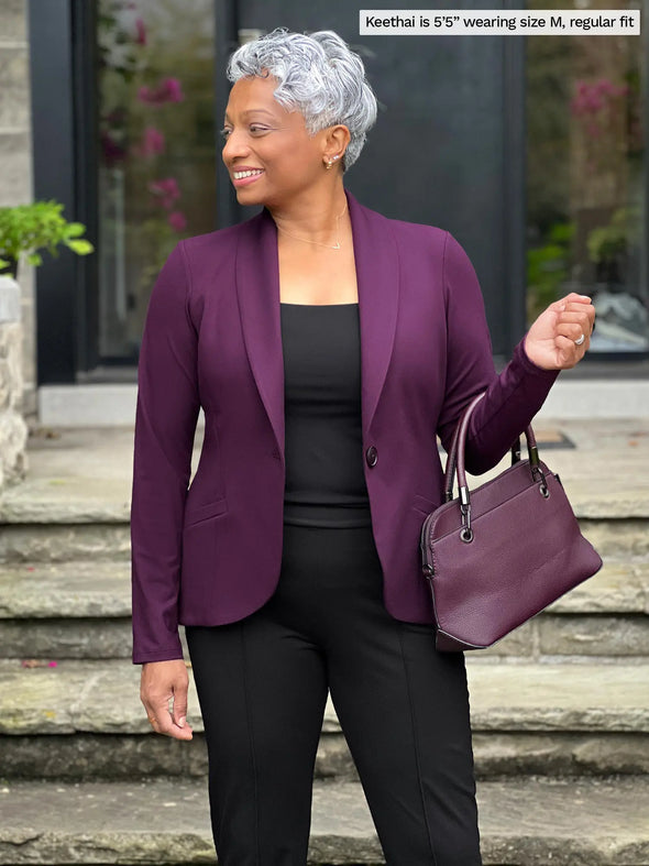 Miik model Keethai (5'5", medium) looking away wearing Miik's Emily soft blazer in port, regular fit, with a dress pant and tank top in black #color_port